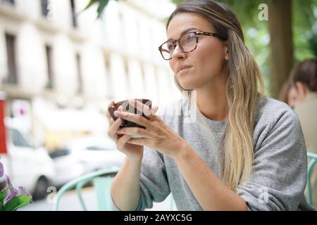 Frau mit Kaffee während sie ihren Blick in eine nachdenkliche Weise Stockfoto