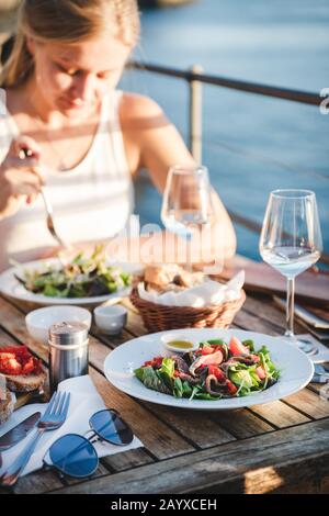 Junge Frau, die im Café mit Blick auf Italien gegessen hat Stockfoto