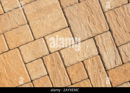 Sehr detailreicher Straßenbelag mit diagonalem geometrischem Muster aus verschiedenen Vierkantblöcken mit strukturierter, rauer Oberfläche in Beige Stockfoto