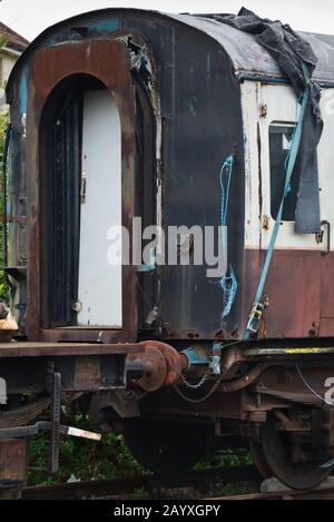 Ein alter Reisewagen, der auf die Wiederherstellung auf einem Abstellplatz am Bahnhof Minehead der West Somerset Railway wartet. Stockfoto