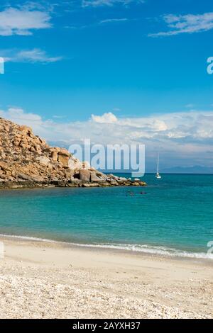 Menschen schnorcheln an einem Strand auf der Isla Espirituo Santo im Bahia de La Paz, Meer von Cortez in Baja California, Mexiko mit segelboot im Backgrou Stockfoto