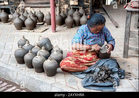 Nepalesische Frau, die Keramik auf dem Pottery Square anstellt, einem öffentlichen Platz voller Töpferräder und Reihen von Tontöpfen - Bhaktapur Nepal Stockfoto