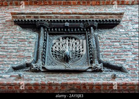 Das Pfauenfenster, ein Fenster aus dem frühen 15. Jahrhundert mit aufwändig geschnitztem Pfau in seiner Mitte, abseits des Dattatraja-Platzes, Bhaktapur, Nepal Stockfoto