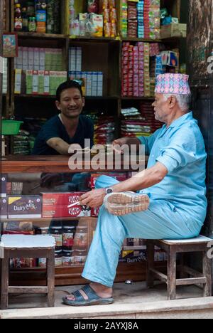 Nicht identifizierte nepalesische Newari-Männer in einem Haberdashery in Bhaktapur, das von der UNESCO als Weltkulturerbe für seine reiche Kultur, Tempel und Kunstwerke aus Holz gelistet ist Stockfoto