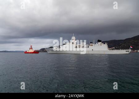 Holländisches Kriegsschiff, Fregatte HNLMS Evertsen F805, Abfahrt vom Hafen von Bergen, Norwegen. Unterstützt von Schleppboot-Boxer. Ein dunkler und regnerischer Wintertag Stockfoto