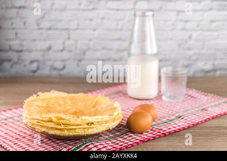 Gesunde traditionelle Pfannkuchen aus Reismehl und ein Glas Milch auf Holztisch Stockfoto