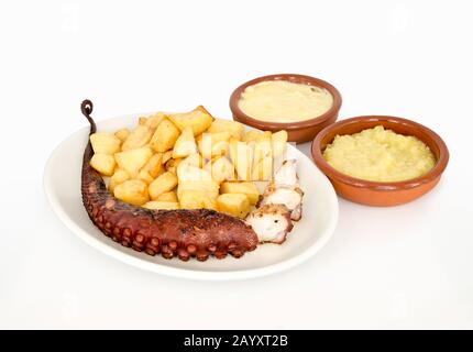 Gericht von Kraken mit Kartoffeln von zwei Saucen in Tontöpfen begleitet Stockfoto