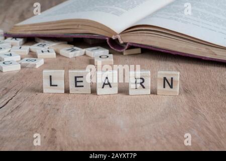 Das Wort lernt geschrieben mit Würfelbuchstaben auf Holzhintergrund Stockfoto
