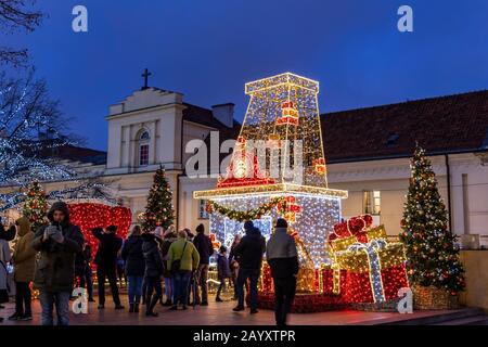 Warschau, Polen - 27. Dezember 2019: Menschen, die in der Stadt die nächtliche Beleuchtung der Weihnachtszeit beobachten Stockfoto