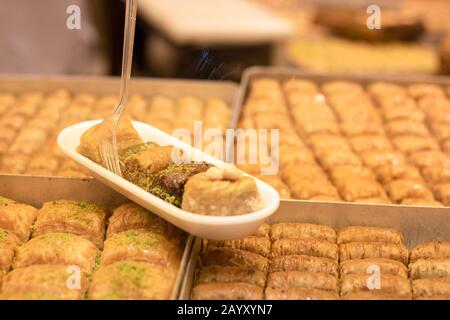 Baklavar wird in verschiedene Geschmacksrichtungen in Kunststoffplatten gegeben und hat eine Kunststoffgabel darauf. Er wurde vor den Markt gebracht. Stockfoto