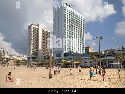 Volleyballspieler im Sand entlang der Promenade von Gordon Beach in Tel Aviv, neben der Hotelzone mit Crowne Plaza und Herodes Hotels. Israel. Stockfoto