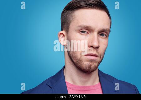 Porträt eines ernsthaften jungen bärtigen Mannes mit blauen Augen vor hellblauem Hintergrund Stockfoto