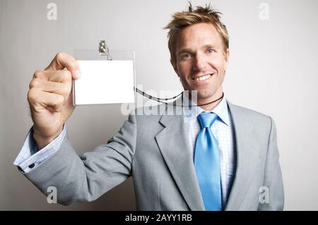 Fröhliche Geschäftsmann, Lächeln, wie er es sich in seinem leeren Namen Tag hält Stockfoto