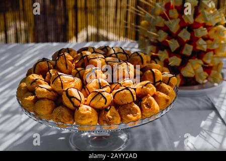 Gericht voller köstlicher und süßer Profiteroles, gefüllt mit kalter Creme. Stockfoto