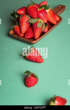 Organische reife Erdbeeren auf Holzplatte auf grünem Tisch. Schmackhafte rote Beeren auf Aqua menthem Hintergrund. Süße Sommerfrüchte. Erdbeerfrüchte stapeln. Stockfoto