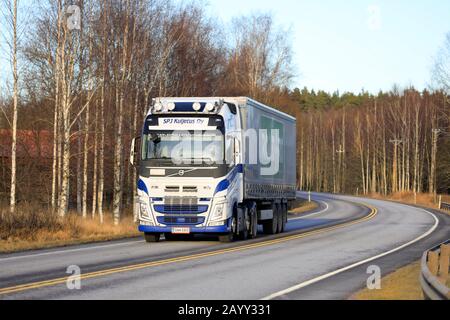 Der blau-weiße Volvo FH-Truck von SPJ Kuljetus Oy zieht im Frühjahr den Anhänger zur Abendsonne entlang der Autobahn 25. Raasepori, Finnland. Februar 2020. Stockfoto