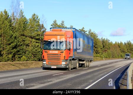 Orange Scania Truck von Tarmekal Oy zieht im Frühjahr den LKW Walter Anhänger in Richtung Hafen von Hanko entlang der Autobahn 25. Hanko, Finnland. Februar 2020. Stockfoto