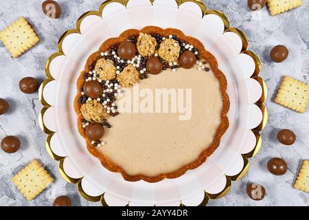 Süßes Tortendessert mit Käsekuchen Milchschokoladencreme, gefüllt mit Pralinen und Schokoladenstreuen, Draufsicht Stockfoto