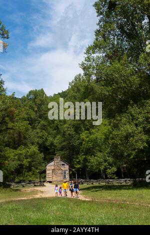 Menschen, die aus dem Besuch der John Oliver Kabine aus den 1820er Jahren in Cades Cove, Great Smoky Mountains National Park in Tennessee, USA, kommen. Stockfoto