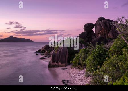 Dämmerung auf Felsen und Meer am Strand von Source D Argent auf La Digue, Seychellen Stockfoto