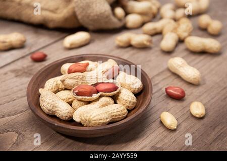 Erdnüsse in der Schüssel auf rustikalem Holztisch. Arachis hypogäa Stockfoto