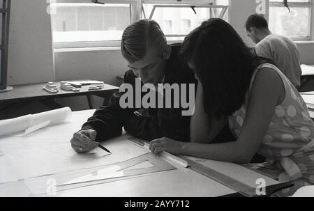 In den 1960er Jahren studieren historische, männliche und weibliche Studenten eine technische Zeichnung auf einem Tisch, der nebeneinander in einer Klasse sitzt, der University of Southern California, USA Stockfoto