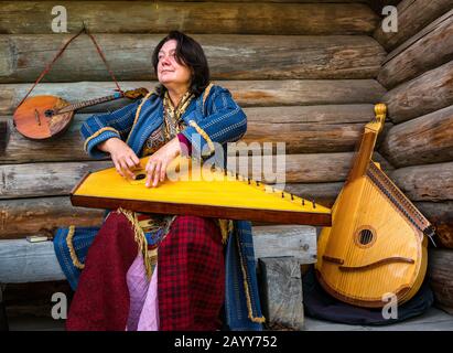 Frau in der Zeit Kostüm spielt Zither oder gusli Streichinstrument, Taltsy Museum of Wooden Architecture, Irkutsk Region, Sibirien, Russland Stockfoto