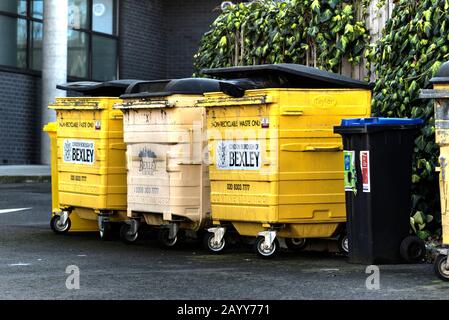Bexley, London, Großbritannien - 8. Februar 2020: Drei große schmutzige gelbe Abfallbehälter, die nicht recycelbaren Abfall enthalten, und ein kleiner Behälter mit r Stockfoto