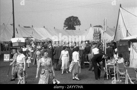 1950er Jahre, historisch, Besucher der Thame Show, Oxfordshire, England, zeigen die Moden, die von Menschen dieser Epoche getragen werden, die durch das gezungene Dorf umherstreifen. Stockfoto