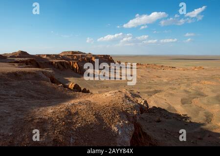 Die orangefarbenen Felsen von Bayan Zag, die im Allgemeinen als Flaming Cliffs in der Wüste Gobi, der Mongolei, bekannt sind und in denen wichtige Dinosaurier-Fossilien gefunden wurden. Stockfoto