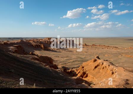 Die orangefarbenen Felsen von Bayan Zag, die im Allgemeinen als Flaming Cliffs in der Wüste Gobi, der Mongolei, bekannt sind und in denen wichtige Dinosaurier-Fossilien gefunden wurden. Stockfoto