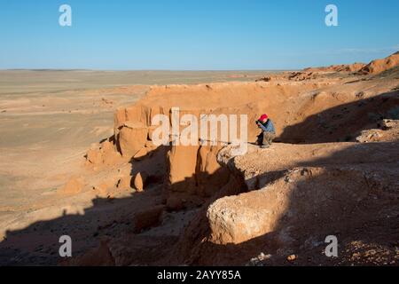 Die orangefarbenen Felsen von Bayan Zag, die im Allgemeinen als Flaming Cliffs in der Wüste Gobi, der Mongolei, bekannt sind und in denen wichtige Dinosaurier-Fossilien gefunden wurden. Stockfoto