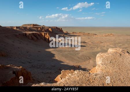 Die orangefarbenen Felsen von Bayan Zag, die im Allgemeinen als Flaming Cliffs in der Wüste Gobi, der Mongolei, bekannt sind und in denen wichtige Dinosaurier-Fossilien gefunden wurden. Stockfoto