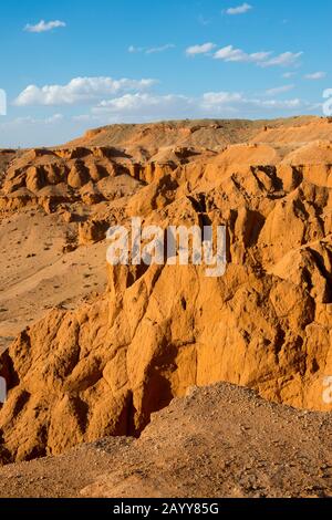 Die orangefarbenen Felsen von Bayan Zag, die im Allgemeinen als Flaming Cliffs in der Wüste Gobi, der Mongolei, bekannt sind und in denen wichtige Dinosaurier-Fossilien gefunden wurden. Stockfoto