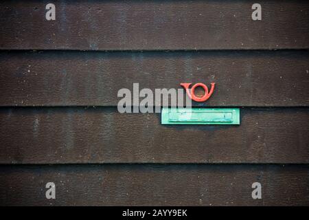 Ein grüner Briefschlitz und ein rotes Schild mit dem Hornpfosten auf schwarzem Holzboardhintergrund Stockfoto