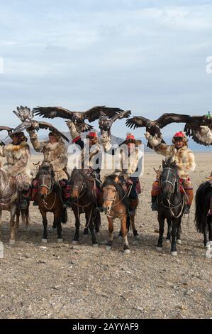 Eine Gruppe kasachischer Adler-Jäger und ihre goldenen Adler posieren nach der Ankunft auf dem Festgelände des Goldenen Adlers in der Nähe der Stadt Ulgii (Ölgii) in Th Stockfoto