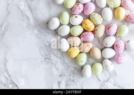 Frohe Ostern Konzept. Vorbereitung für den Urlaub. Ostern Eier in Pastellfarben Süßigkeiten Schokolade Bonbons auf trendige grauem Marmor Hintergrund. Einfache Minimalismus flach Ansicht von oben kopieren Raum Stockfoto
