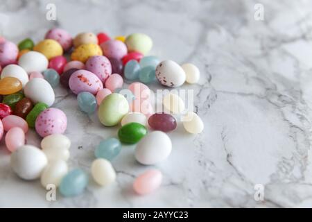 Frohe Ostern Konzept. Vorbereitung für den Urlaub. Ostern Süßigkeiten Schokolade Eier und fruchtgummi Bonbons auf trendige grauem Marmor Hintergrund. Einfache Minimalismus flach Ansicht von oben kopieren Raum Stockfoto