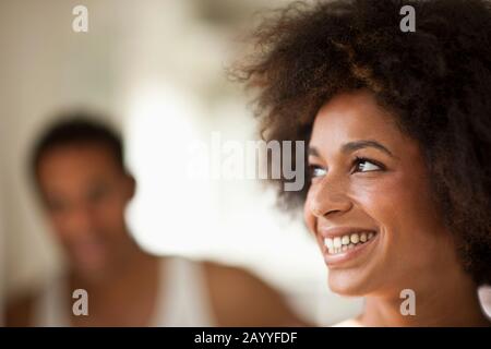 Fröhliche junge Frau, die aufblickt, während ihr Freund im Hintergrund steht. Stockfoto