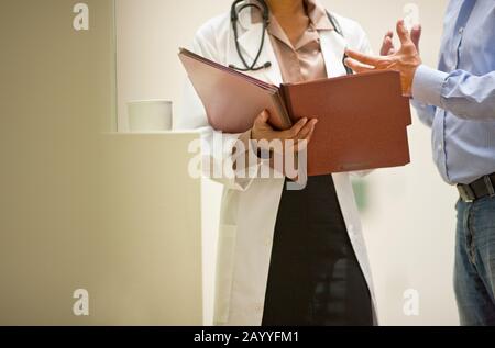 Männliche und weibliche Arzt diskutieren Patientenakten. Stockfoto