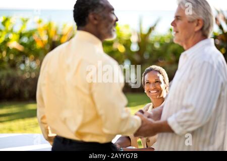 Zwei Männer schüttelten die Hände vor Geschäftsfrau. Stockfoto
