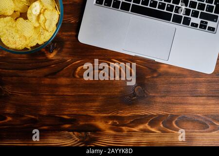 Glasplatte mit Spänen neben einem Laptop auf gebranntem Holzhintergrund. Kopierbereich. Nahaufnahme. Stockfoto