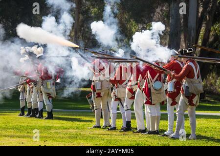 Britische Rotkitter-Soldaten feuern Musketen während einer Nachstellung der amerikanischen Revolution im Huntington Central Park Huntington Beach, Kalifornien, USA Stockfoto