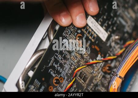 Professioneller Mann repariert und montiert den Computer im Inneren. Steckerhand fügt Grafikkarte in Computer ein. Konzept des Diagnoseservice und Reparaturcom Stockfoto