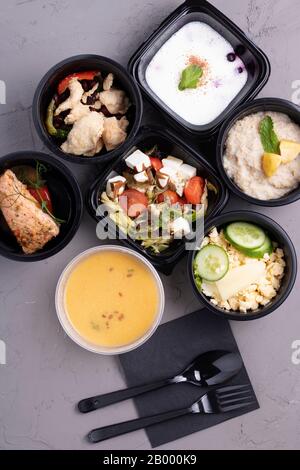 Leckeres Mittagessen in Kunststoffbehältern auf grauem Tisch in der Nähe, Draufsicht Stockfoto