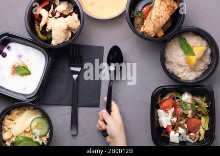 Vegane Mahlzeit, Reis, Salat, Avocado, Kohl, Cremetuppe auf grauem Grund, flacher Lay. Köstliches Balanced Food-Konzept, Kind mit schwarzem Löffel und Gabel Stockfoto