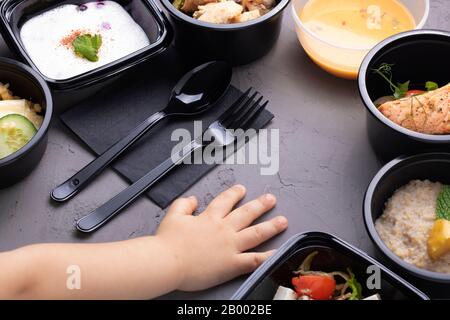 Kinder reichen in der Nähe von Kisten mit köstliches Essen, Lunchbox mit Reis, gemischtem Gemüse, gekochtem Ei, Nüssen und Kürbiscremesuppe, Draufsicht, flacher Lay Stockfoto