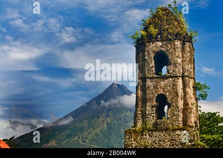 Der Vulkan Mayon, der für seinen perfekten Kegel bekannt ist, ist ein beliebtes Touristenziel. Die Ruinen von Cagsawa sind Reste einer franziskanischen Kirche aus dem 16. Jahrhundert. Stockfoto