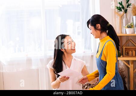 Seitenansicht der weiblichen Teenager, Paper Postcard als Geschenk an Frau mittleren Alters zu Hause auf Tagfahrlicht Stockfoto