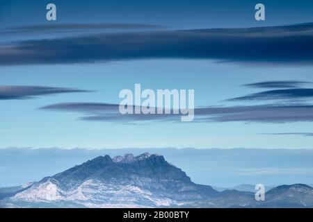 Berg aus Granit mit blauer Atmosphäre und großen Wolken, Montserrat, Katalonien Stockfoto